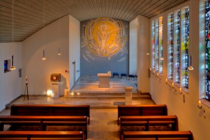Blick von der Orgelempore in Richtung Chorraum. Der Auferstandene Christus hell von Scheinwerfern angestrahlt.